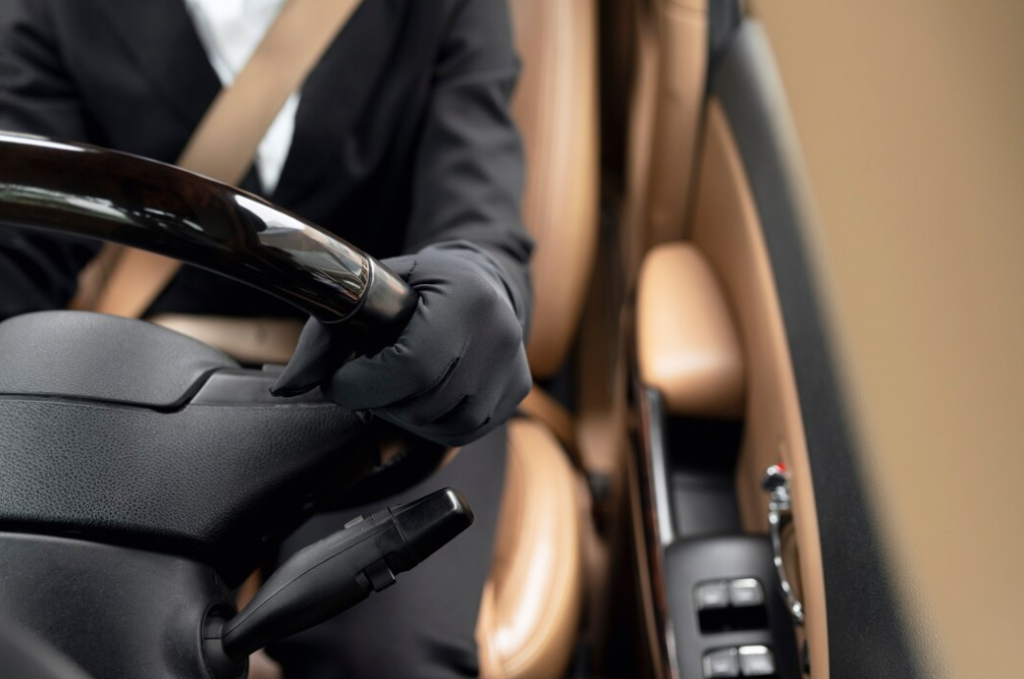 A close-up view of a well-dressed driver with black gloves inside a luxury vehicle.