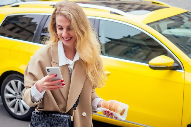 Female holding phone and pastry, taxi in the background